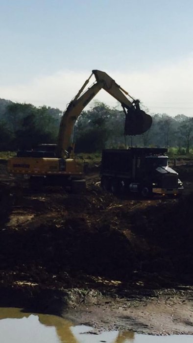 Excavator loading a dump truck at sunrise