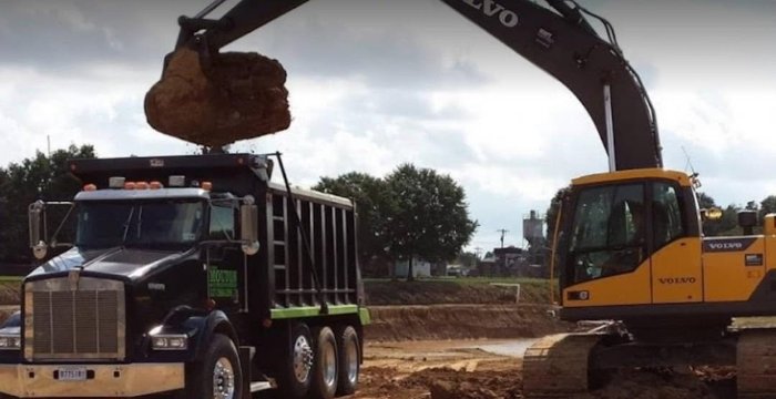 Volvo excavator loading a Mouton dump truck on a land-prep job