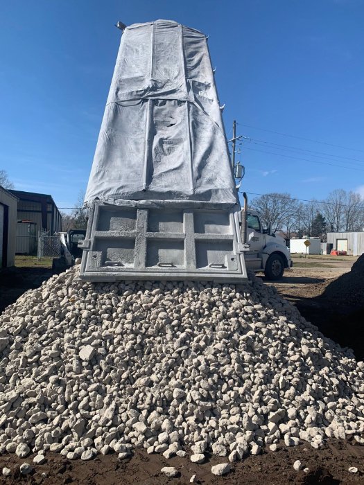 Dump truck tailgate over a fresh pile of limestone